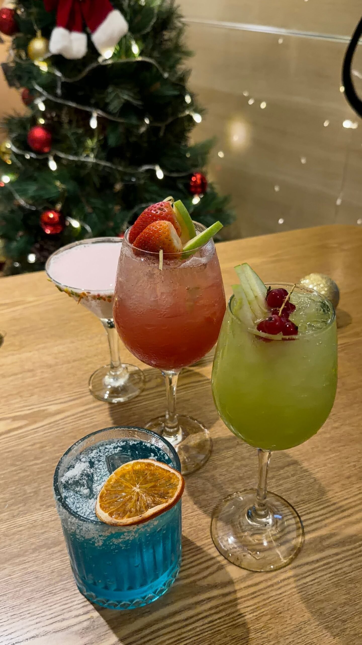 Festive Christmas cocktails in front of a decorated holiday tree