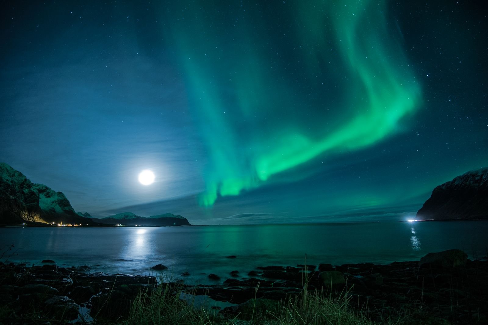 Green northern lights glowing over a calm lake in Norway