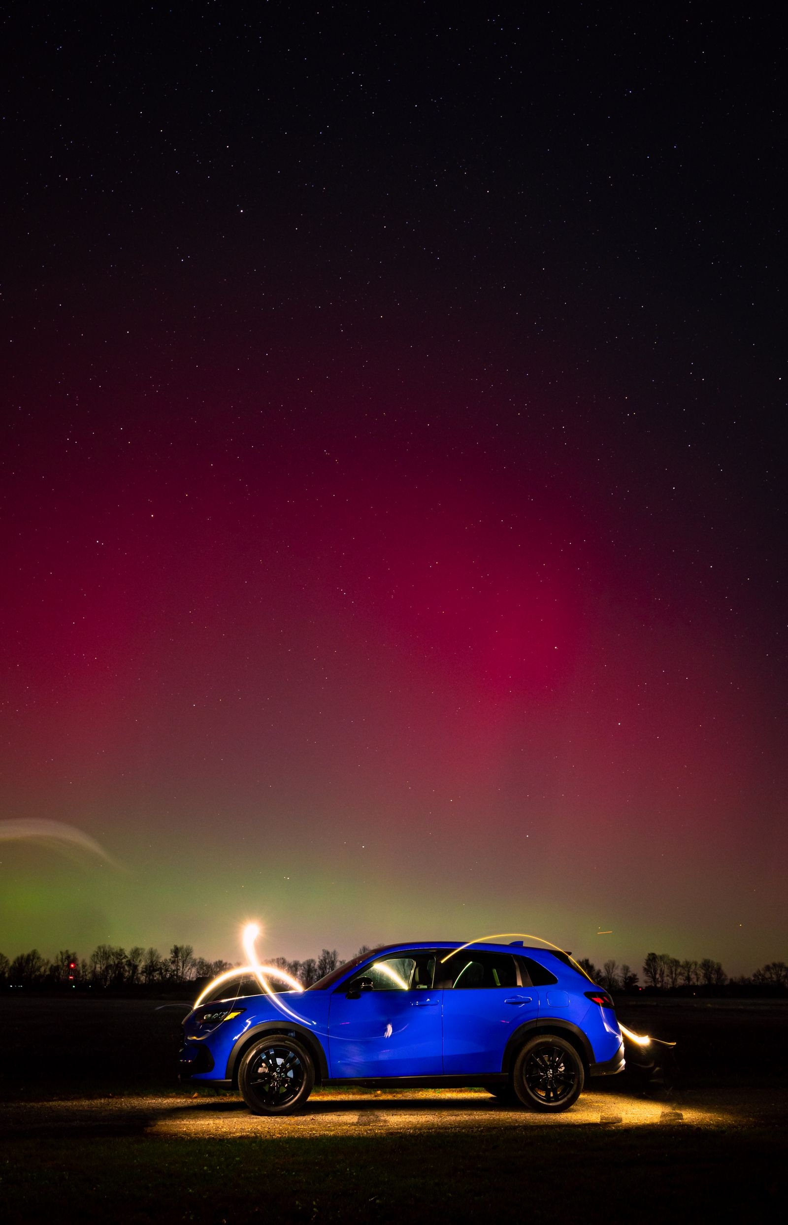 Car parked under a bright aurora-filled night sky