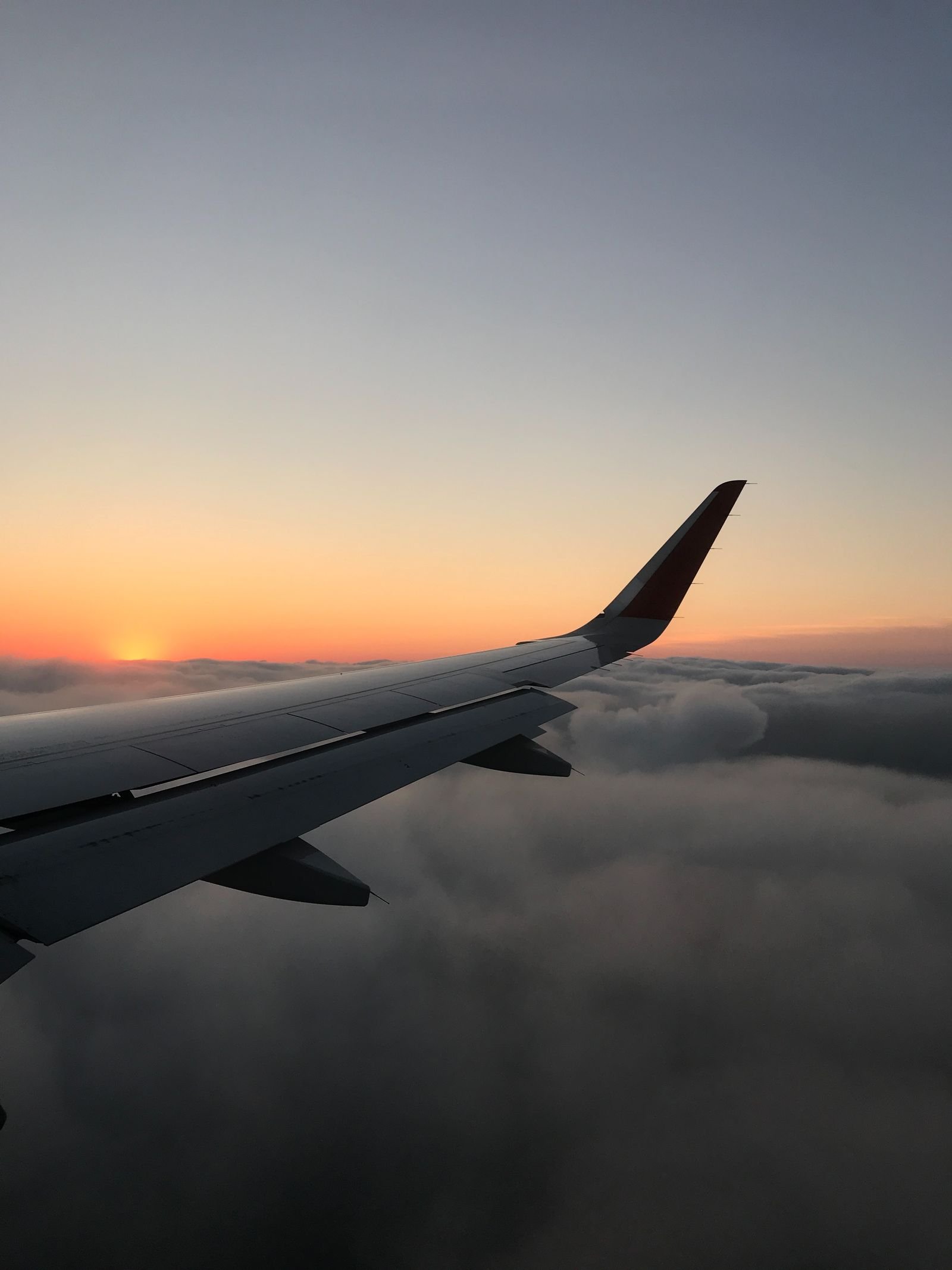 Airplane wing above the clouds at sunset